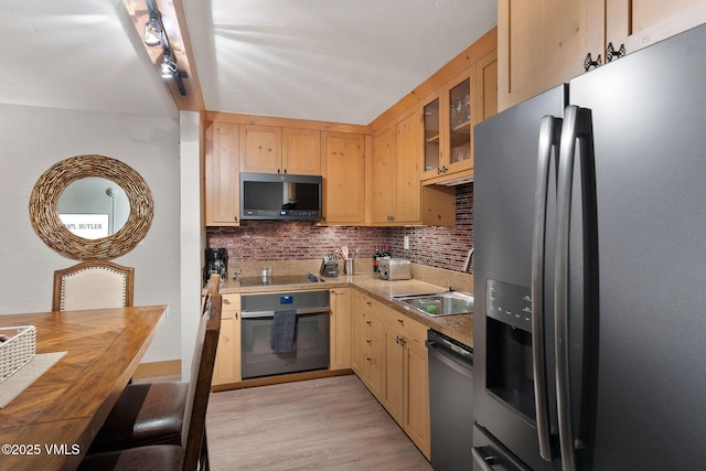 kitchen featuring light brown cabinets, light hardwood / wood-style floors, decorative backsplash, and black appliances