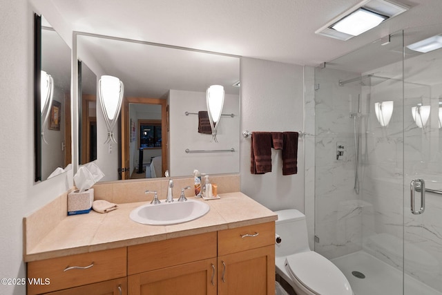 bathroom featuring vanity, toilet, and a shower with door