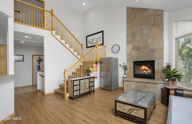 1082 W Wildwood Rd Unit C, Avon, CO 81620 - living room featuring light wood-type flooring, high vaulted ceiling, stairway, a stone fireplace, and recessed lighting