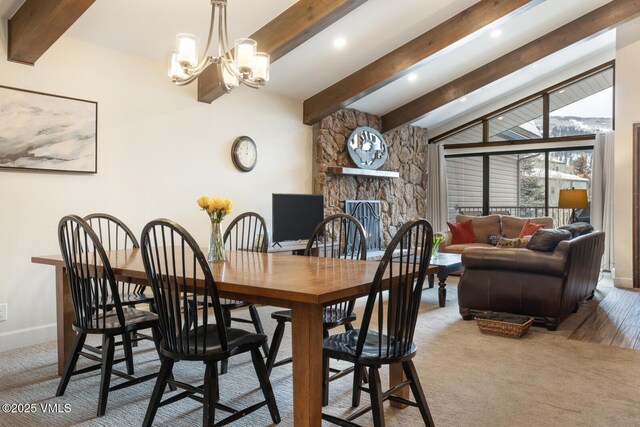 dining space with beam ceiling, a stone fireplace, and a chandelier