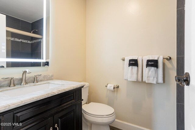 bathroom featuring vanity, a shower with door, and toilet