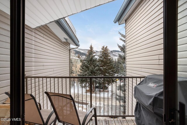 snow covered back of property featuring a mountain view and area for grilling