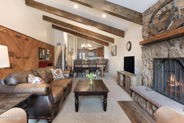 carpeted living room featuring vaulted ceiling with beams, a fireplace, and a chandelier