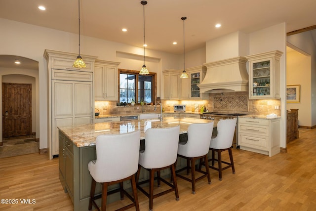 96 Pikes Way, Edwards, CO 81632 - kitchen with cream cabinets, a center island with sink, a breakfast bar area, light wood-style floors, and decorative backsplash