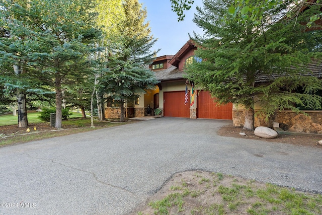 57 Mccoy Creek Dr Unit A, Edwards, CO 81632 - view of property hidden behind natural elements with stone siding, asphalt driveway, and a garage