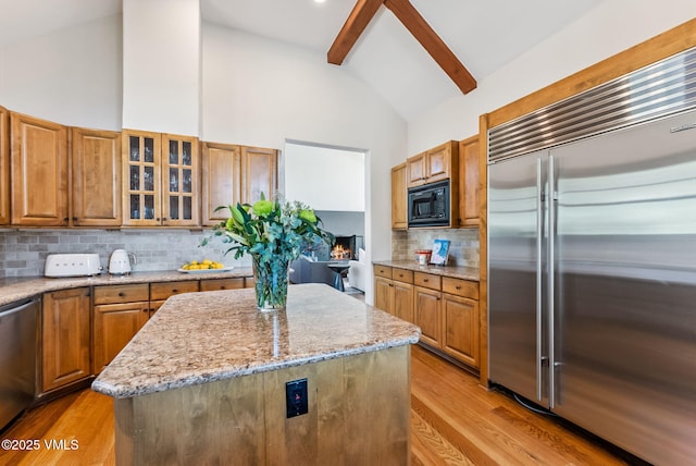 196 Spring Creek Ln, Edwards, CO 81632 - kitchen with built in appliances, light stone counters, brown cabinetry, and a kitchen island