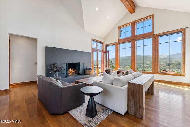 196 Spring Creek Ln, Edwards, CO 81632 - living room featuring high vaulted ceiling, wood finished floors, beamed ceiling, a warm lit fireplace, and healthy amount of natural light
