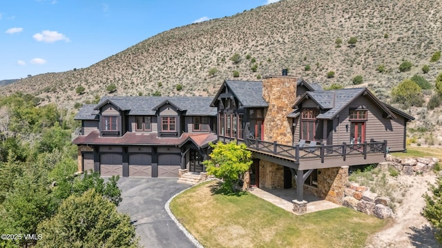 196 Spring Creek Ln, Edwards, CO 81632 - view of front of property with driveway, stone siding, an attached garage, a chimney, and a front lawn