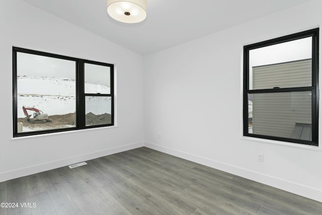 spare room with hardwood / wood-style flooring and vaulted ceiling