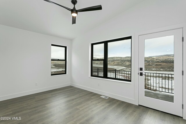 unfurnished room featuring ceiling fan, a mountain view, vaulted ceiling, and hardwood / wood-style floors