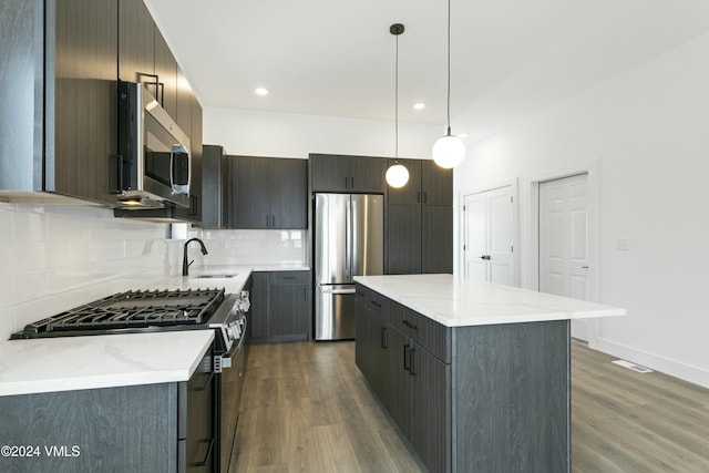 kitchen with pendant lighting, sink, appliances with stainless steel finishes, a center island, and decorative backsplash