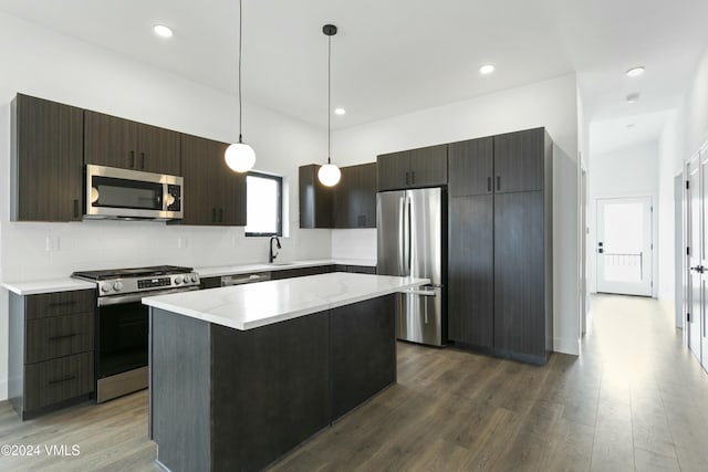 kitchen with dark hardwood / wood-style floors, stainless steel appliances, decorative light fixtures, and a kitchen island