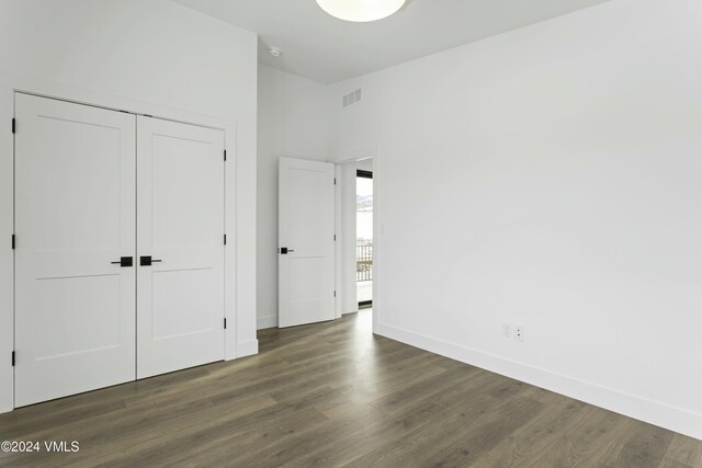 unfurnished bedroom featuring dark hardwood / wood-style flooring and a closet