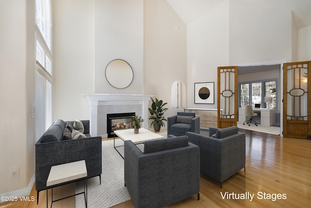 living room featuring hardwood / wood-style flooring, a high ceiling, and a fireplace