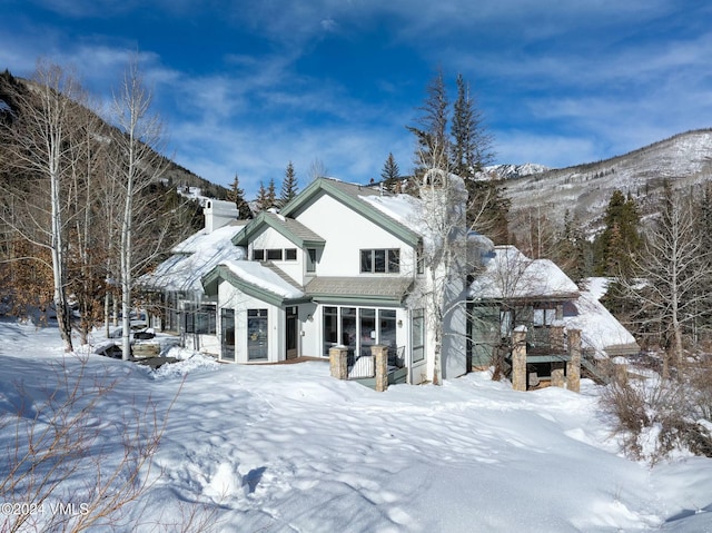 snow covered rear of property with a mountain view