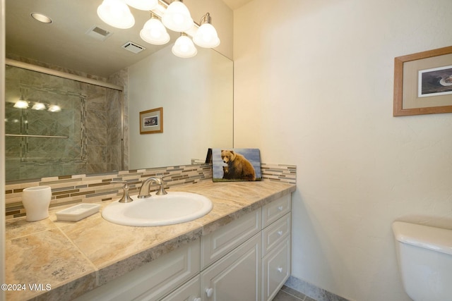 bathroom with backsplash, a chandelier, vanity, an enclosed shower, and toilet