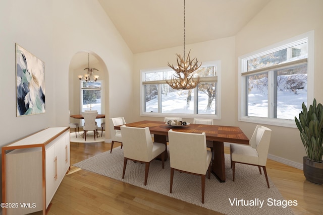 dining area with vaulted ceiling, a notable chandelier, and light hardwood / wood-style floors