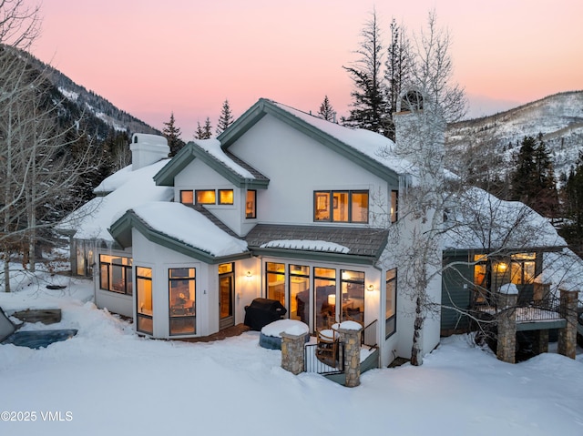 snow covered back of property with a mountain view