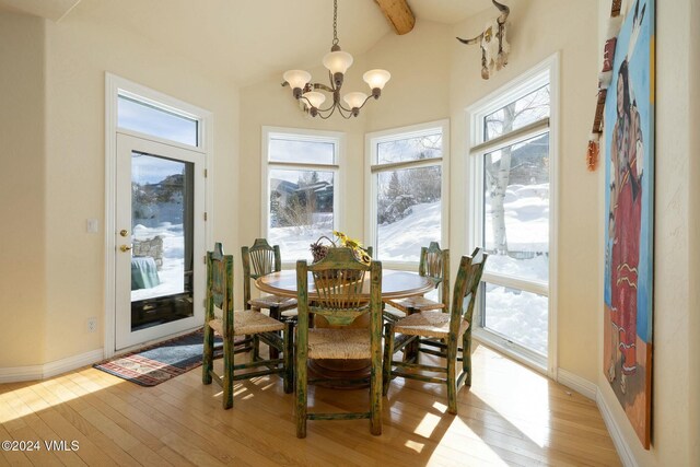 dining area featuring a notable chandelier, vaulted ceiling with beams, and light wood-type flooring