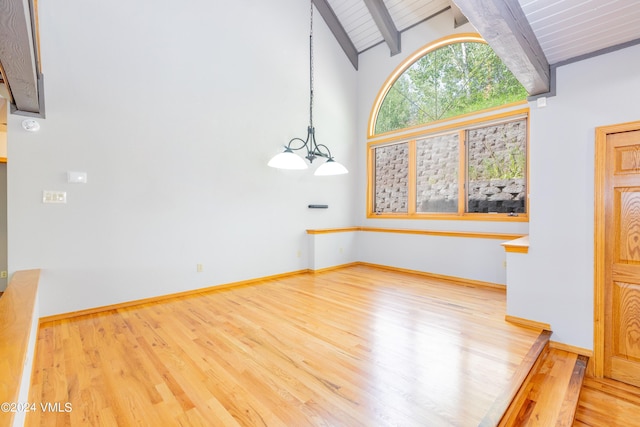 unfurnished living room with high vaulted ceiling, beamed ceiling, a notable chandelier, wooden ceiling, and light hardwood / wood-style flooring