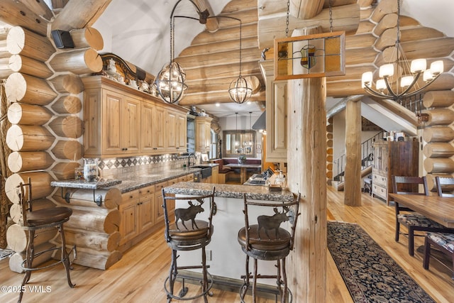 1416 Red Draw, Edwards, CO 81632 - kitchen with a chandelier, log walls, light wood finished floors, a breakfast bar, and dark stone countertops