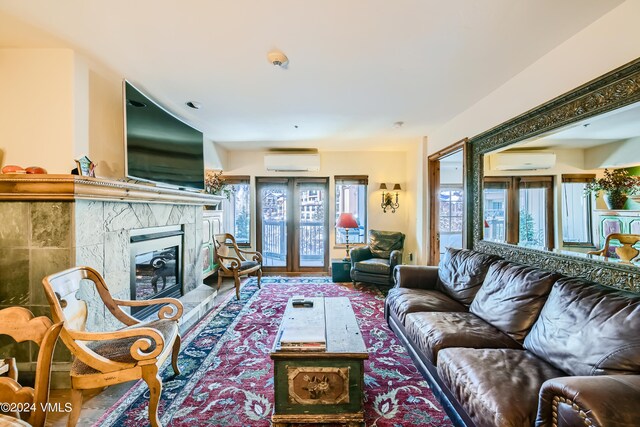 living room featuring a high end fireplace, a wall unit AC, and french doors