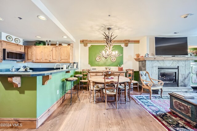 kitchen with a breakfast bar, decorative light fixtures, light brown cabinetry, and light wood-type flooring