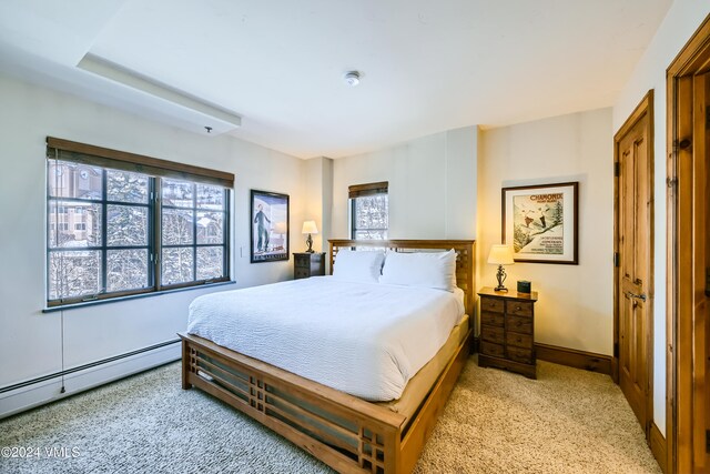 bedroom with light carpet and baseboard heating