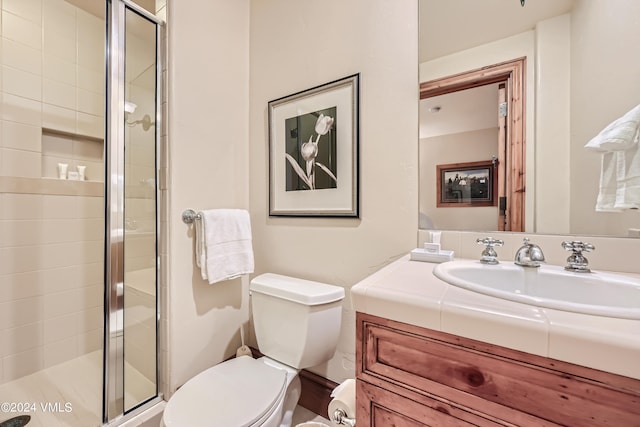 bathroom featuring a shower with door, vanity, and toilet