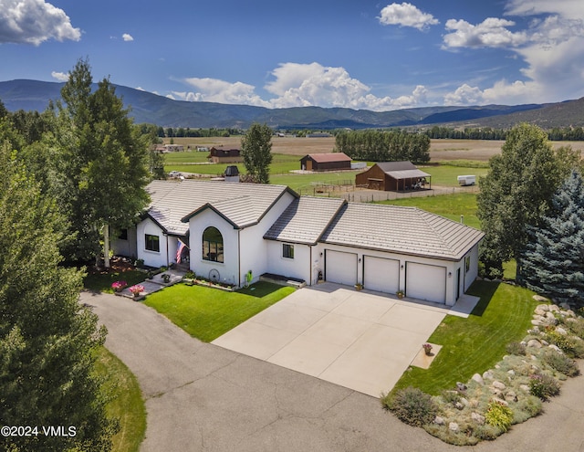 view of front of house with a garage, a mountain view, and a front lawn