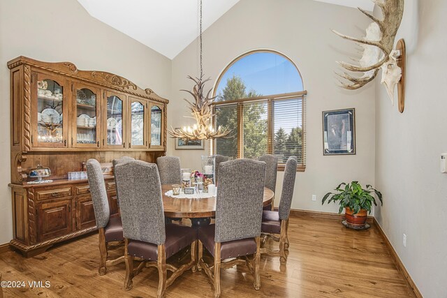 dining space with high vaulted ceiling, a notable chandelier, and light wood-type flooring