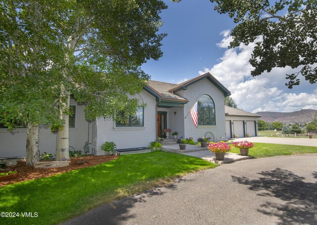 view of front facade featuring a garage, a mountain view, and a front lawn