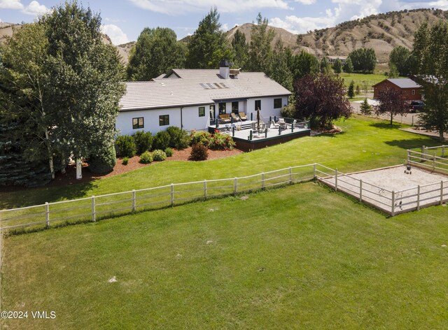 back of property with a mountain view, outdoor lounge area, a rural view, and a lawn