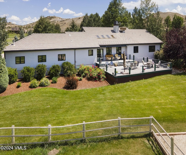 rear view of property with an outdoor hangout area, a mountain view, and a lawn