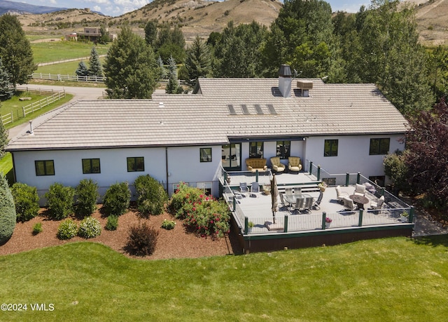 rear view of property featuring a mountain view, an outdoor hangout area, and a lawn