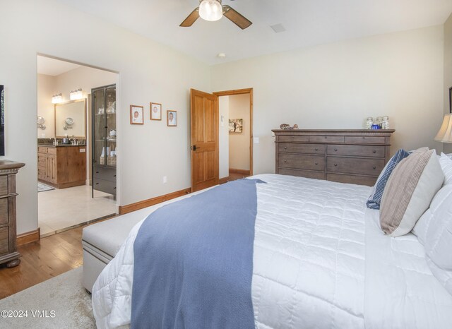 bedroom with ceiling fan, ensuite bathroom, and light hardwood / wood-style floors