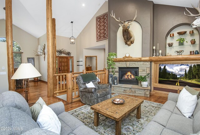 living room featuring wood-type flooring, a fireplace, high vaulted ceiling, and built in features