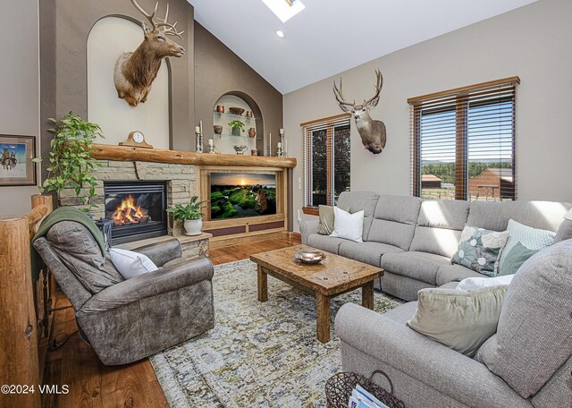 living room with hardwood / wood-style flooring, high vaulted ceiling, a fireplace, and built in shelves