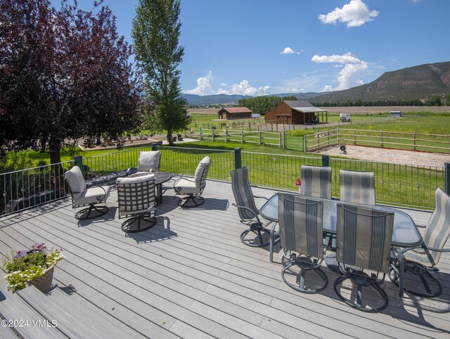 wooden terrace featuring a mountain view, a rural view, and a lawn