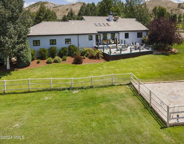 back of house featuring a mountain view and a yard