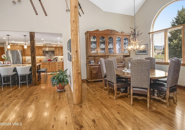 dining room featuring a notable chandelier, high vaulted ceiling, and light hardwood / wood-style floors