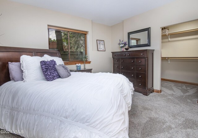 bedroom featuring light colored carpet, a closet, and a walk in closet