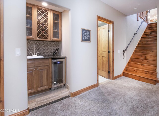 bar with wine cooler, sink, tasteful backsplash, and light colored carpet