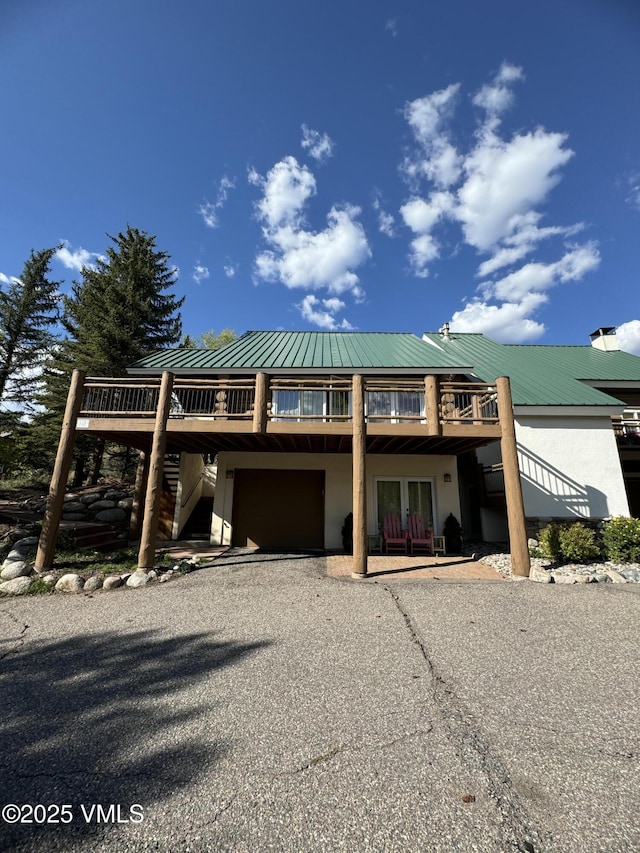 view of front of house featuring metal roof, driveway, a garage, and a wooden deck