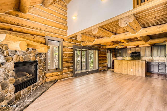 121 Hackamore Rd Unit A, Edwards, CO 81632 - unfurnished living room with a wood ceiling with exposed beams, log walls, wood finished floors, and a stone fireplace