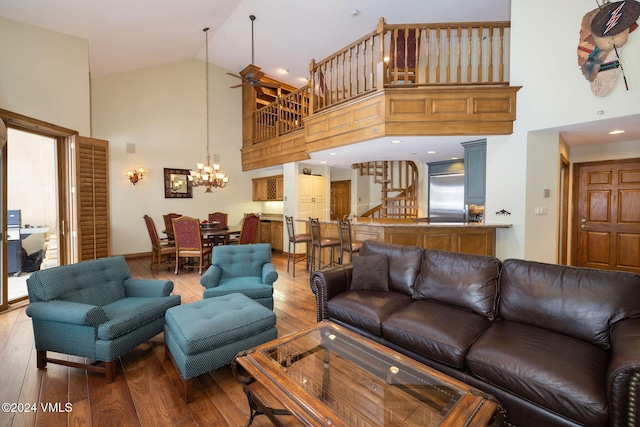 living area with ceiling fan with notable chandelier, high vaulted ceiling, stairs, and hardwood / wood-style floors