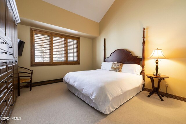 bedroom with light colored carpet, baseboards, and vaulted ceiling