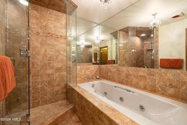 bathroom with an inviting chandelier, a shower stall, and a jetted tub