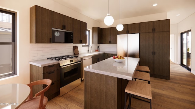 kitchen featuring hanging light fixtures, light hardwood / wood-style flooring, a center island, and appliances with stainless steel finishes