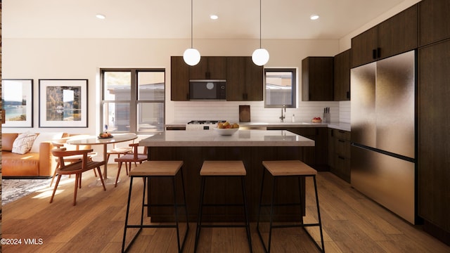 kitchen featuring pendant lighting, stainless steel fridge, backsplash, light hardwood / wood-style floors, and a kitchen island